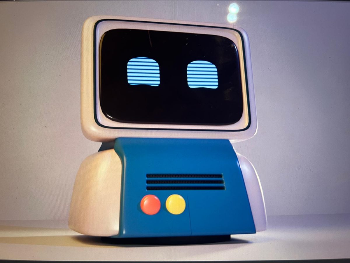 A render of a small robot with a screen for a face showing two eyes, a blue body with a speaker grille, and red and yellow buttons.