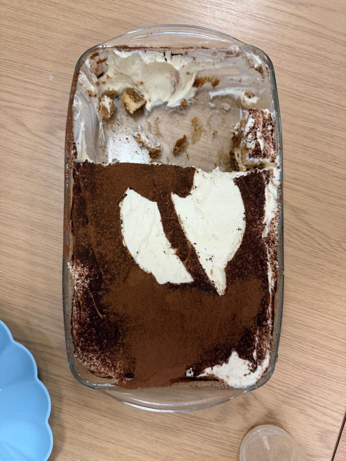 A glass dish of tiramisu, half eaten.