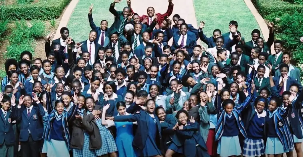 A large group of SSP scholars in school uniform, cheering on a lawn.
